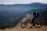 A cyclist pausing on a scenic overlook, with vaun accessories visible on their bike.