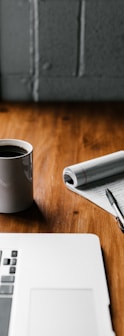 MacBook Pro, white ceramic mug,and black smartphone on table