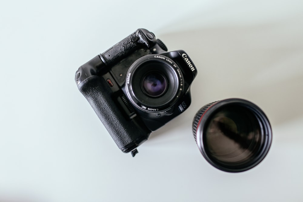 black Canon DSLR camera beside lens