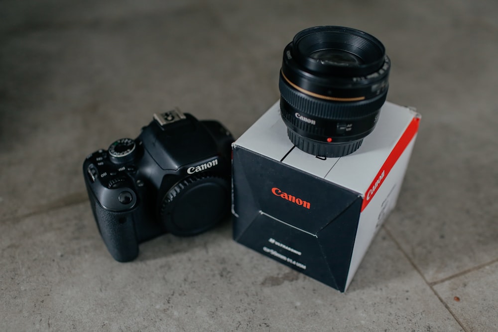 schwarze Canon Kamera mit Objektiv und Box