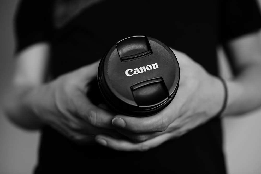man holding Canon camera lens