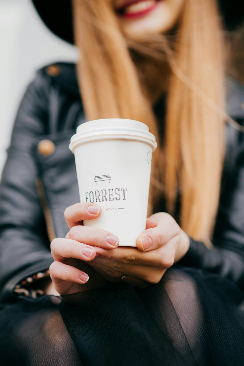 woman holding white Forrest cup with lid selective focus photography