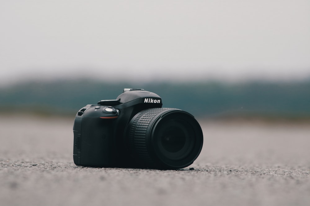 fotografía de enfoque selectivo de una cámara Nikon DSLR negra sobre una superficie de hormigón