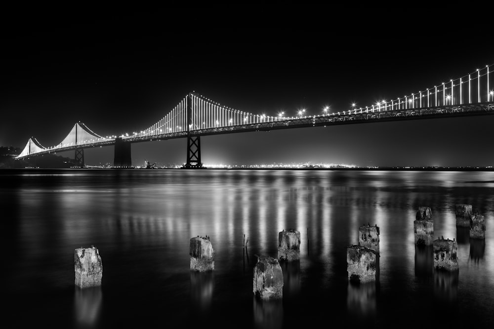 grayscale photography of lightened full-suspension bridge