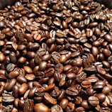 Close-up of coffee beans glistening with morning light and delicate steam rising.