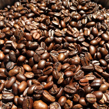 Close-up of coffee beans glistening with morning light and delicate steam rising.