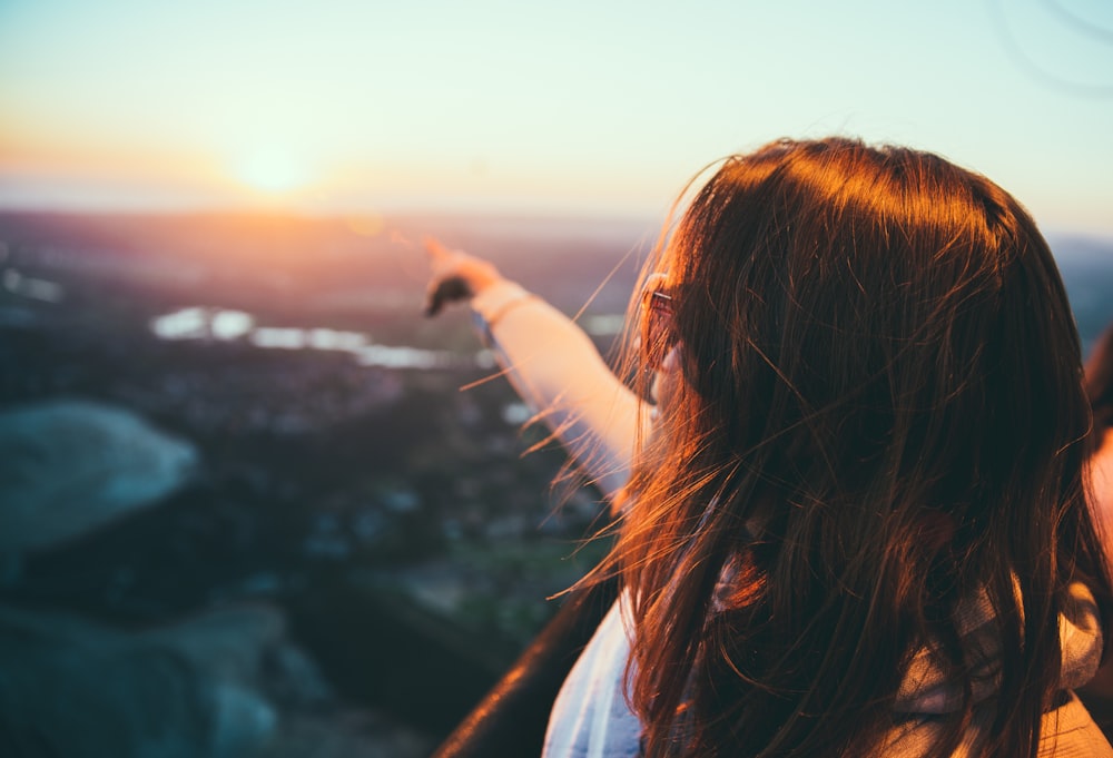 selective focus photography of woman pointing on sky