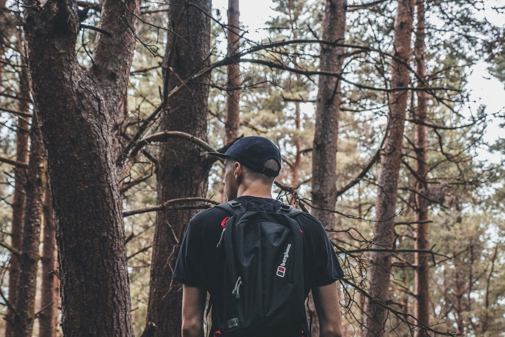 man carrying black backpack on froest