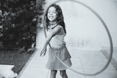 grayscale photography of girl playing with hula hoop