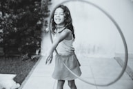 grayscale photography of girl playing with hula hoop