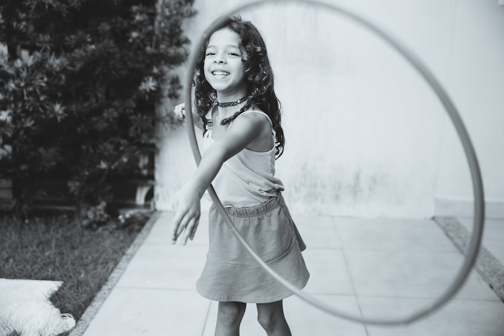 Fotografía en escala de grises de niña jugando con hula hoop