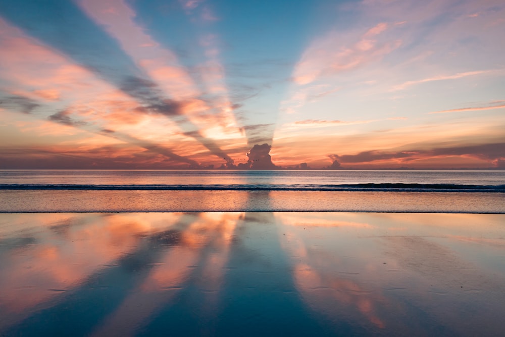 Rays from the sunset burst through the Daytona Beach clouds and reflect perfectly on the calm sea waters