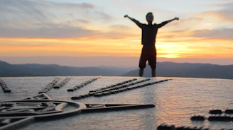 A traveler happily pointing at a map with a bright sunset in the background.