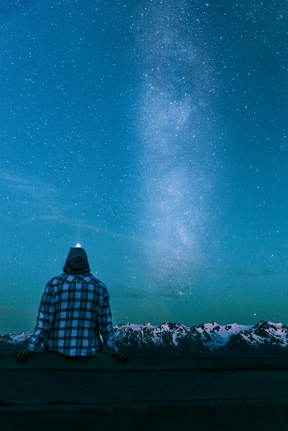 man sitting on gray wall looking at the stars