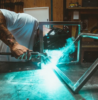 man welding two rectangular gray metal frames