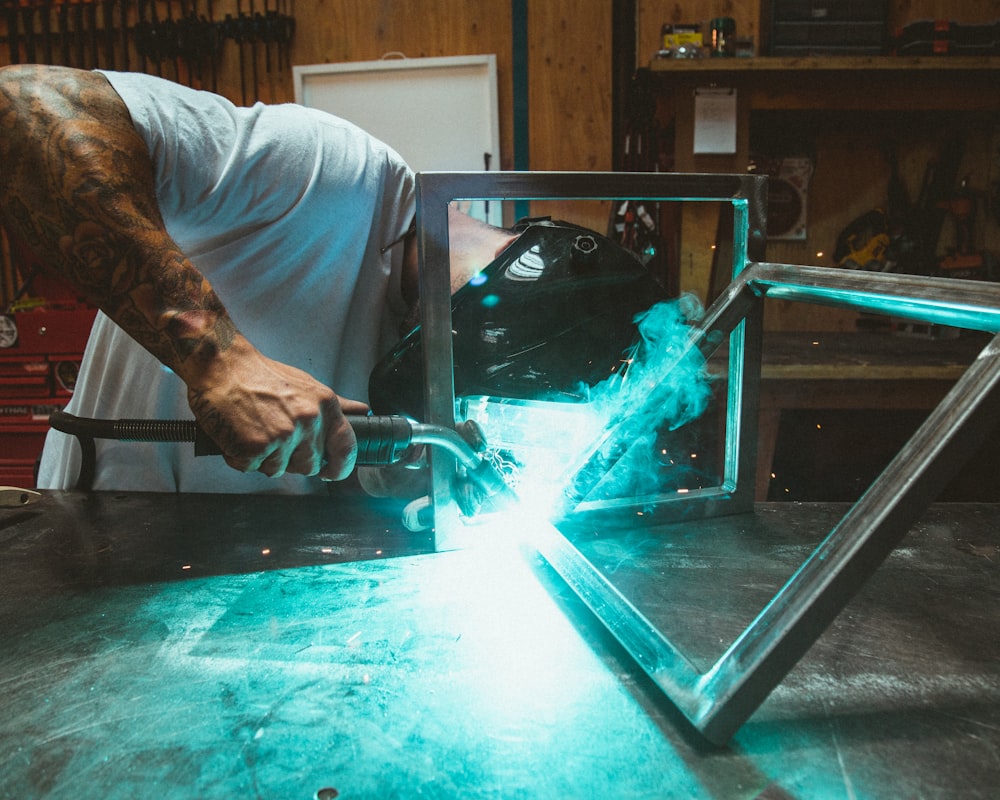 man welding two rectangular gray metal frames