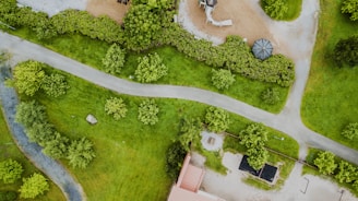 A panoramic view of a lush green residential complex with walking paths and playgrounds under a clear blue sky.
