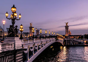 Ornate Paris bridge illuminated at dusk, representing European journeys within Christine's custom tr