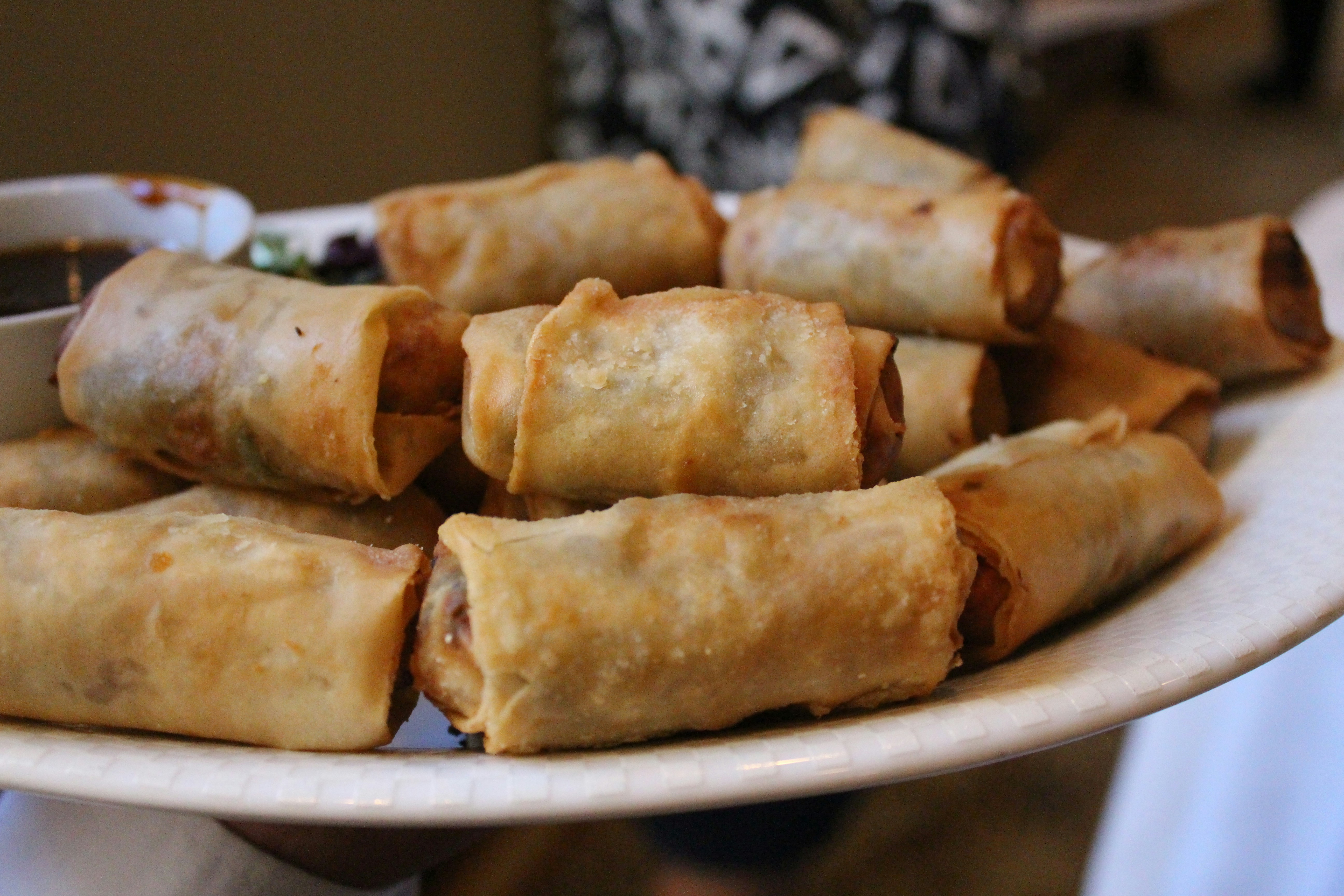 Crispy golden spring rolls with dipping sauce, bright food photography