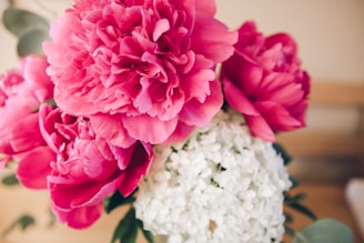 A close-up of a vibrant, freshly picked bouquet featuring soft pink peonies and wild greenery.