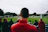 man standing while watching soccer during daytime