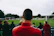 man standing while watching soccer during daytime