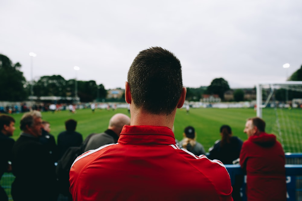 Man at the Guiseley Football Club watching the game and wearing a red jacket
