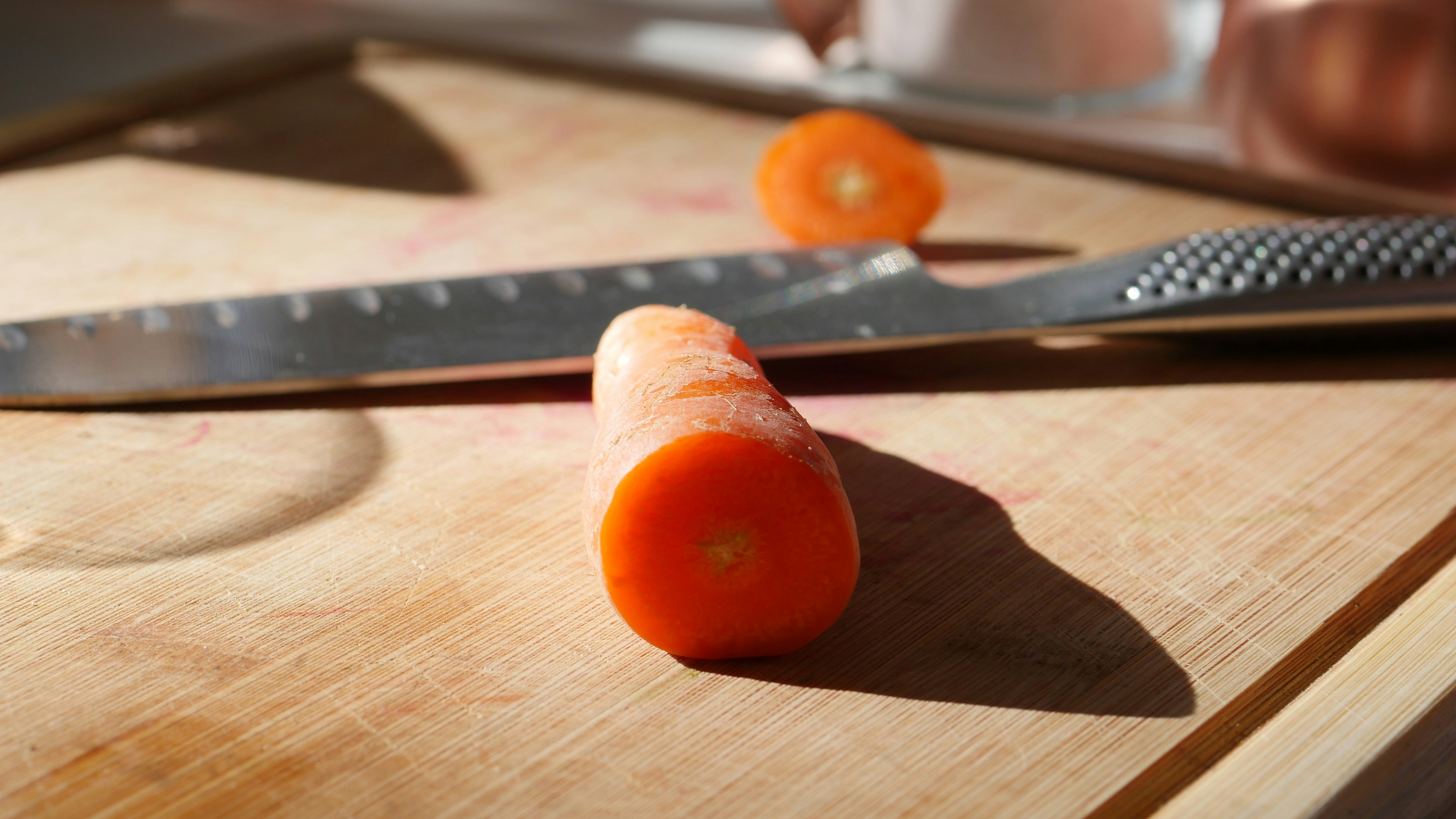 Bright orange kitchen utensil on a wooden cutting board, warm natural kitchen lighting, food photography