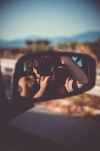 person taking selfie through vehicle wing mirror