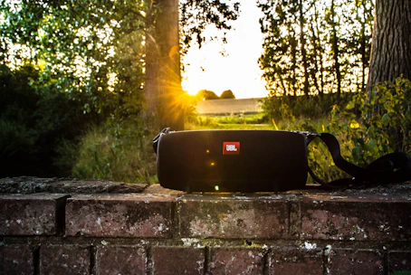 A compact wireless speaker playing music outdoors with vibrant city lights in the background