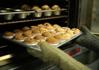 person holds tray of muffins on tray