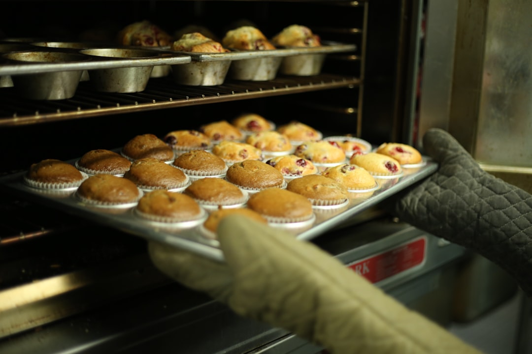  person holds tray of muffins on tray oven