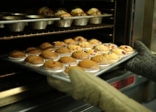 person holds tray of muffins on tray