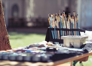 selective focus photography of assorted-shape-and-color paintbrushes on rack