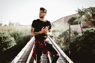 man standing on railroad near plants handsome zoom background