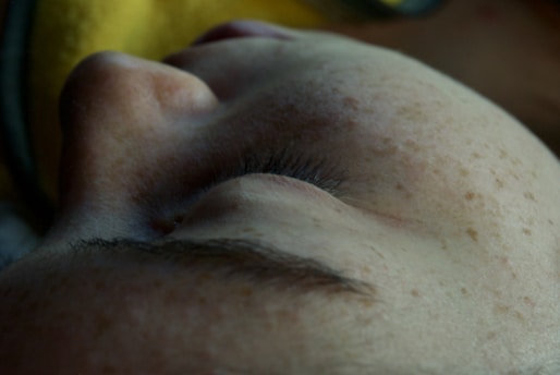 Close-up of a dermatologist examining a patient's skin with gentle lighting.