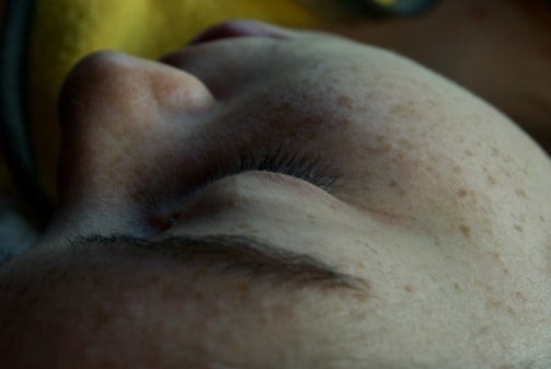 Close-up of a sun-kissed cheek with delicate semi-permanent freckles tattoo.