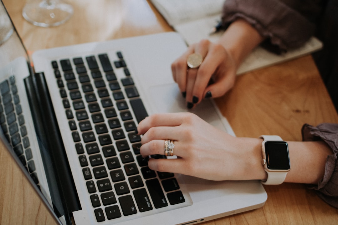 A woman's hands on the keyboard of a laptop in a café