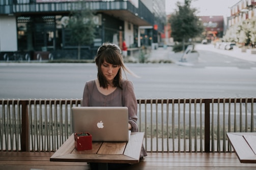 woman in gray shirt sitting on bench in front of MacBook