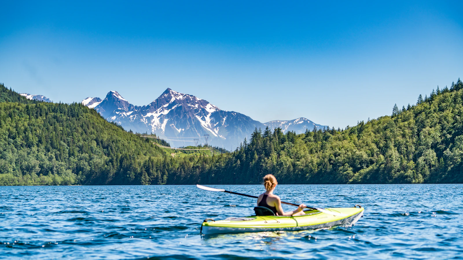 Kayaker crossing a mountain lake in outdoor conditions