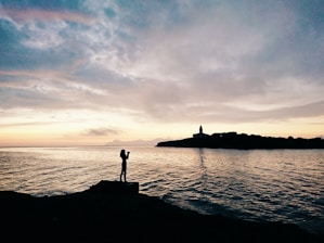 woman standing on rock formation near shoreline