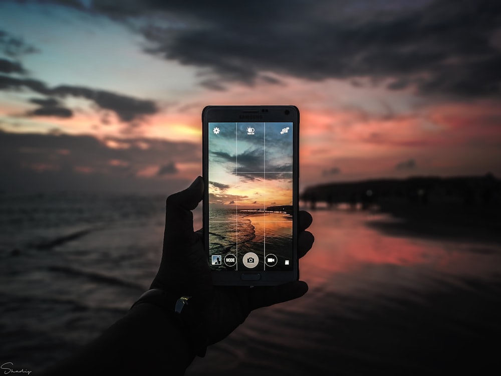 Schwarzes Smartphone macht Foto vom Horizont der goldenen Stunde