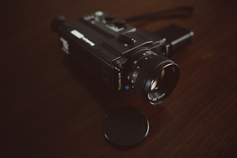 black video camera on brown wooden surface