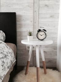 black alarm clock at 10:10 on white wooden table near table
