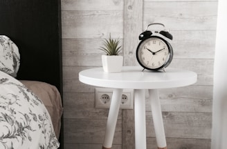 black alarm clock at 10:10 on white wooden table near table