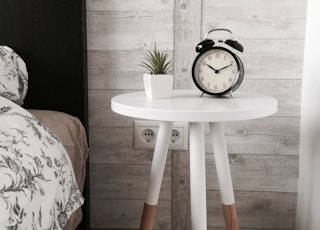 black alarm clock at 10:10 on white wooden table near table