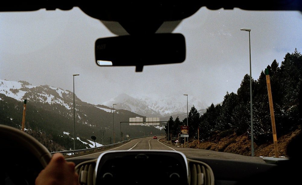 A person road tripping on the highway towards the snowcapped mountains of Andorra
