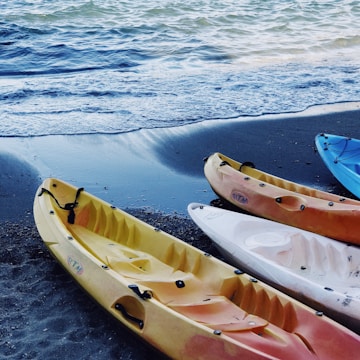 four assorted-color kayaks on seashore