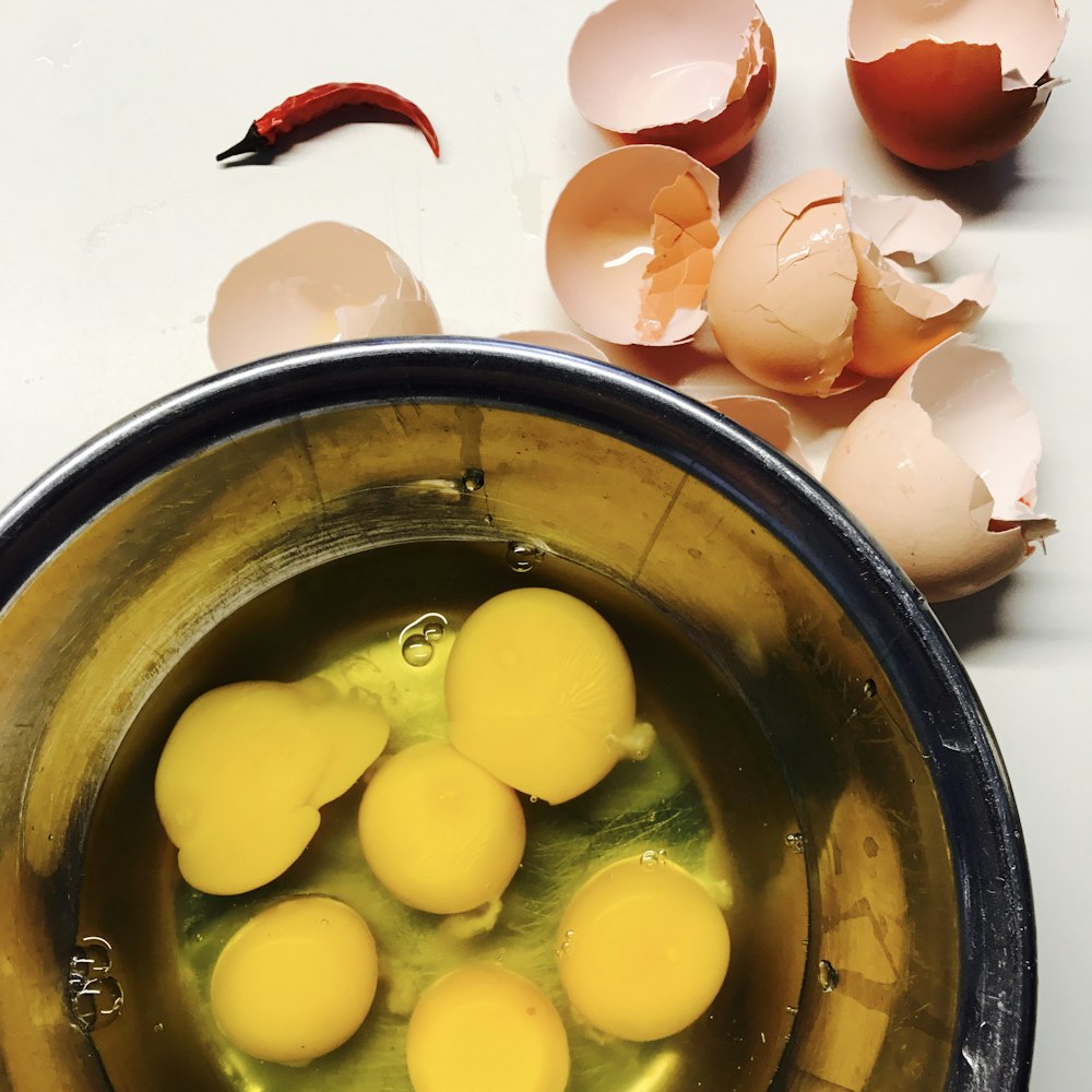 cracked eggs beside round blue bowl