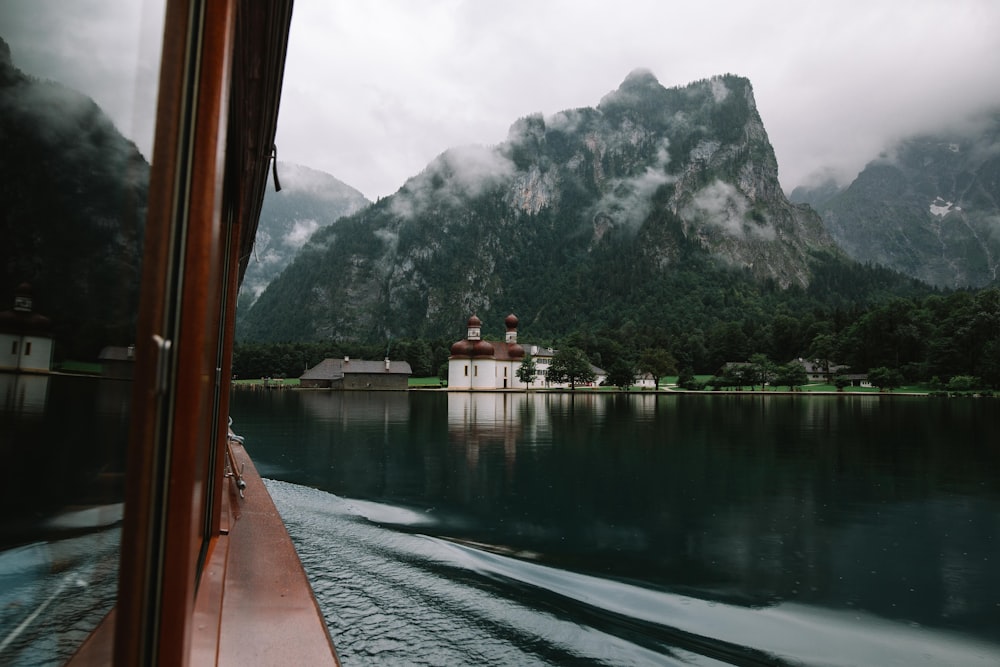 山の写真の前の水域に茶色の木造船